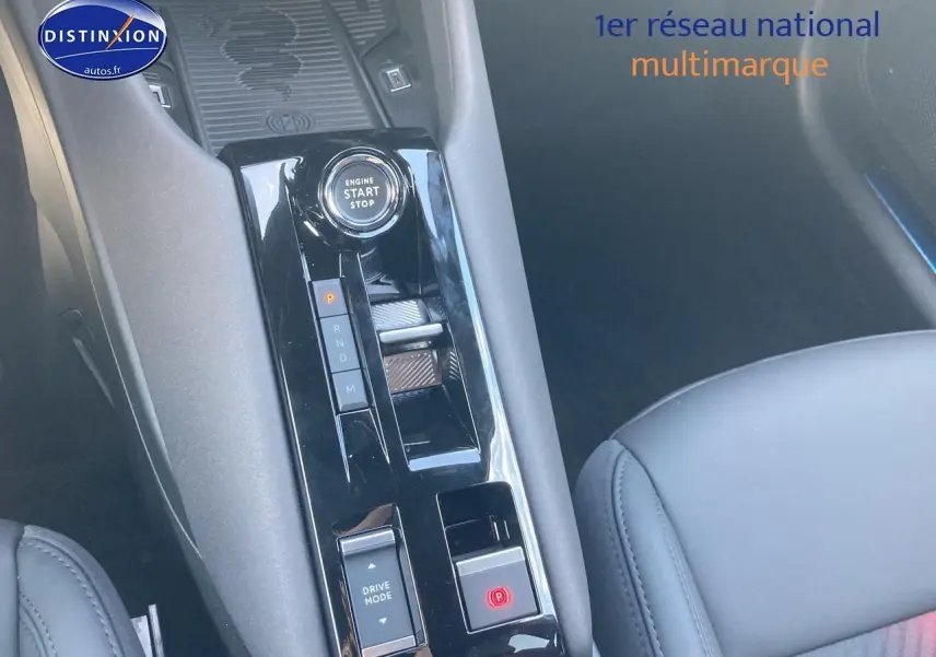 Gros plan sur la console centrale noire brillante de l'Alfa Romeo Junior 1.2 hybride, avec bouton start/stop et levier de boîte auto.