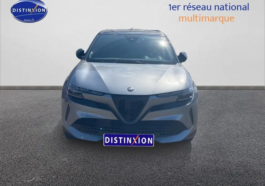 Vue frontale d'une Alfa Romeo Junior 1.2 hybride 2026 gris métallisé avec calandre caractéristique en V et phares LED fins.
