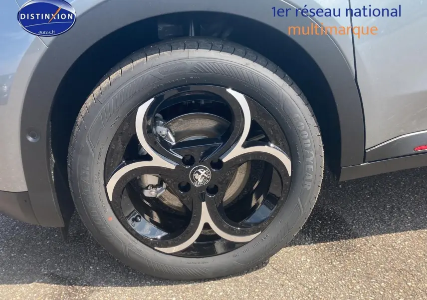 Gros plan sur la roue avant gauche de l'Alfa Romeo Junior 1.2 hybride gris t/noir avec jante alliage noire et argent.
