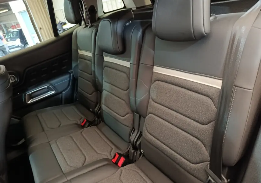 Vue intérieure des sièges arrière en tissu et cuir noir du Citroën C5 Aircross 2024, avec ceintures et appuie-têtes visibles.