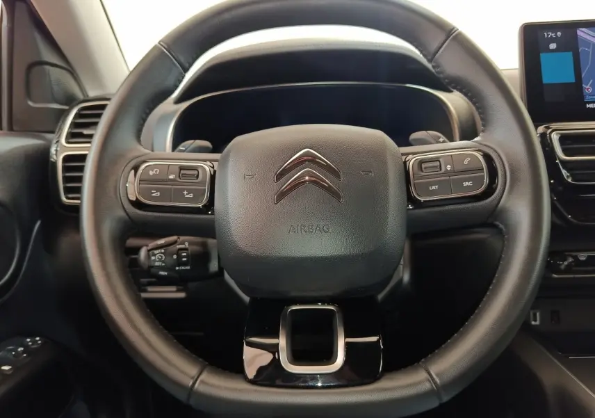 Vue centrée sur le volant cuir noir du Citroën C5 Aircross 2024 avec commandes multifonctions et tableau de bord numérique.