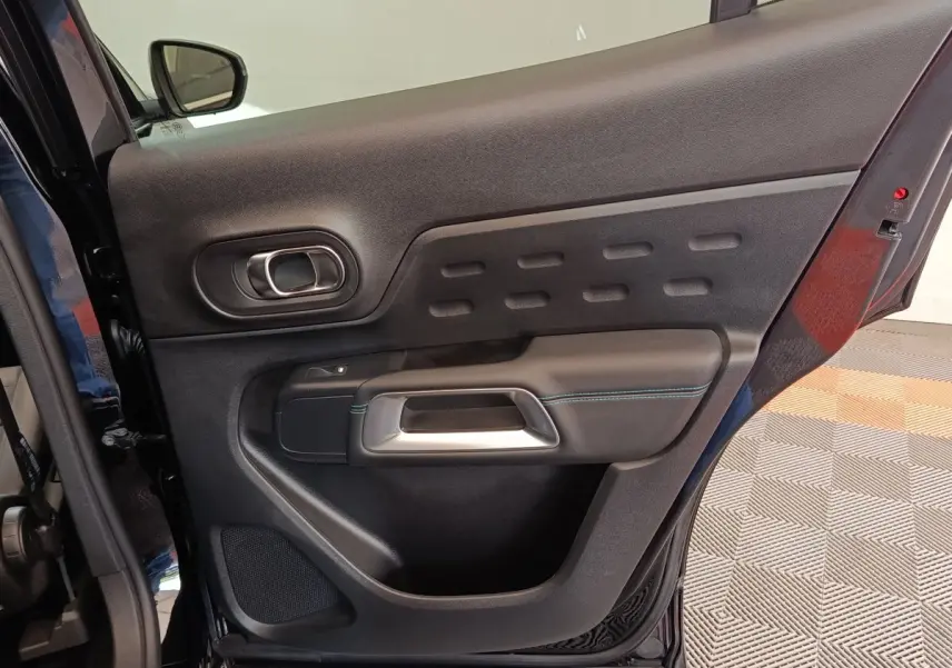 Vue intérieure de la porte arrière droite noire du Citroën C5 Aircross 2024 avec poignée argentée et surpiqûres bleues.