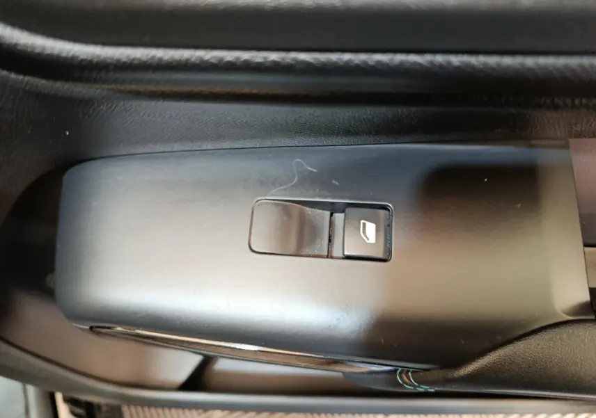 Bouton de commande de lève-vitre noir sur la portière intérieure d'un Citroën C5 Aircross 2024.