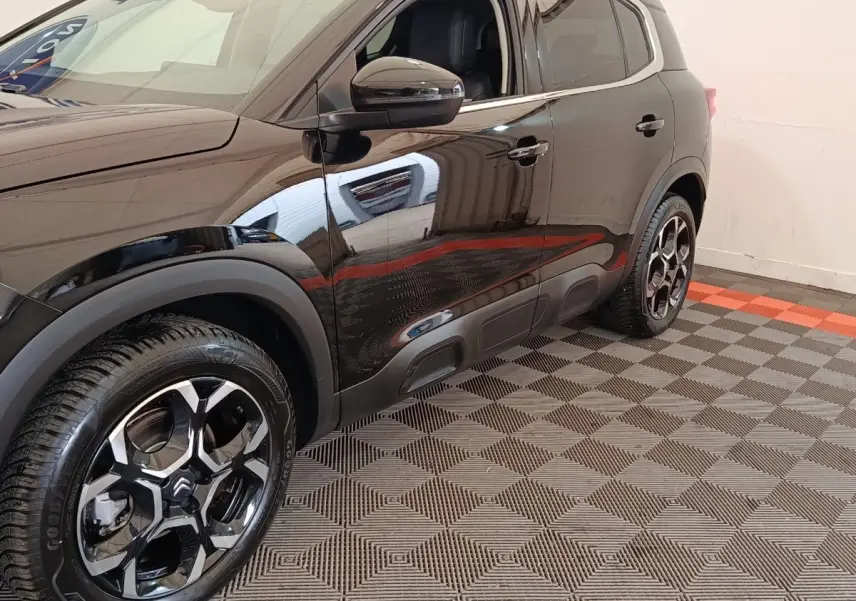 Vue côté gauche avant d'un Citroën C5 Aircross noir 2024 avec jantes noires brillantes et protections latérales.