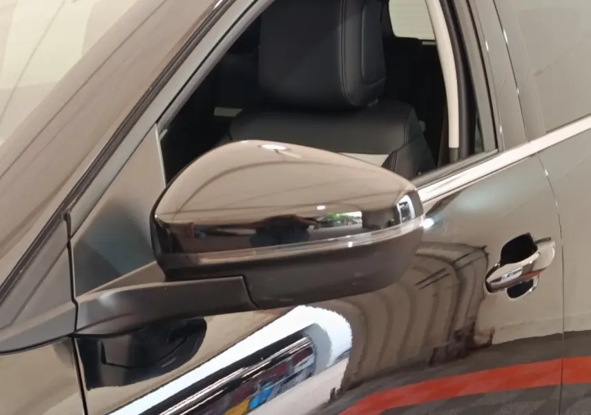 Gros plan sur le rétroviseur côté gauche et la porte noire brillante d'une Citroën C5 Aircross 2024.