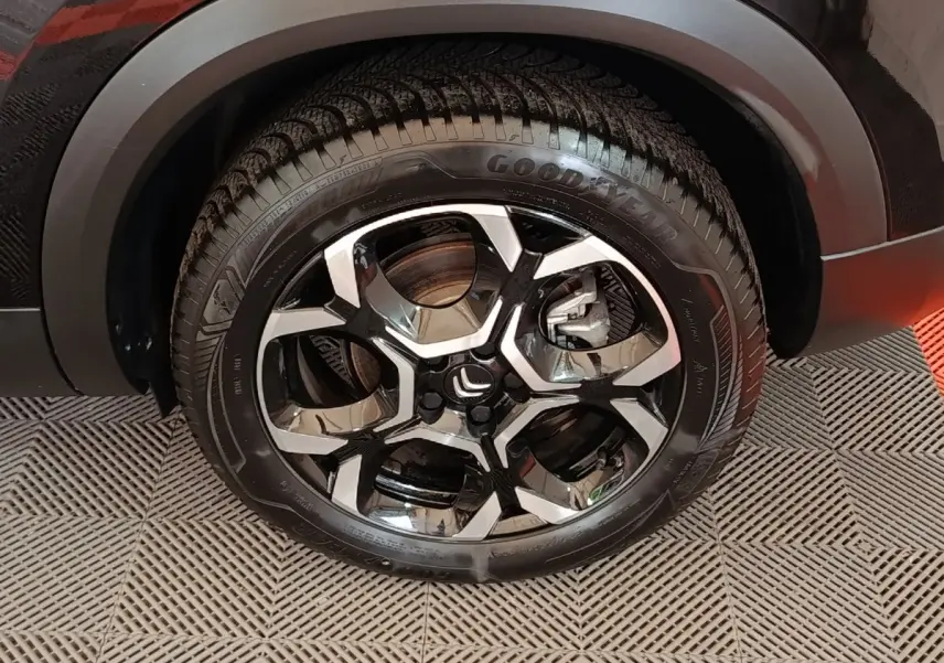 Gros plan sur la roue avant droite noire du Citroën C5 Aircross 2024 avec jante alliage bicolore et pneu Goodyear.