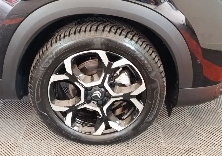 Gros plan sur la roue avant droite noire d'un Citroën C5 Aircross 2024 avec jante alliage bicolore distinctive.