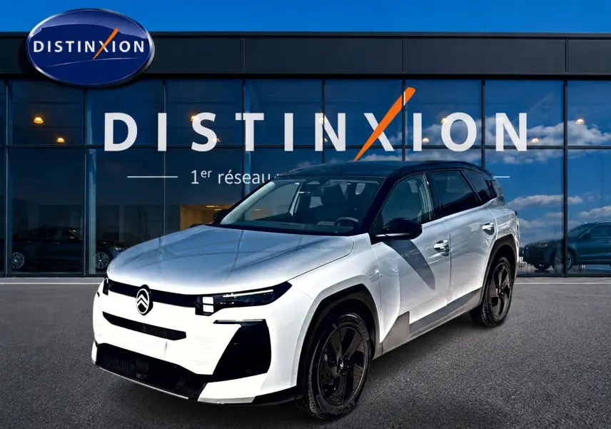 Vue 3/4 avant d'un Citroën C5 Aircross 2026 blanc avec toit noir et jantes alliage noires devant un showroom Distinxion.