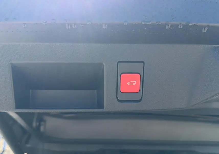 Bouton rouge d'ouverture électrique du hayon sur le bord intérieur du coffre d'un Citroën C5 Aircross blanc.