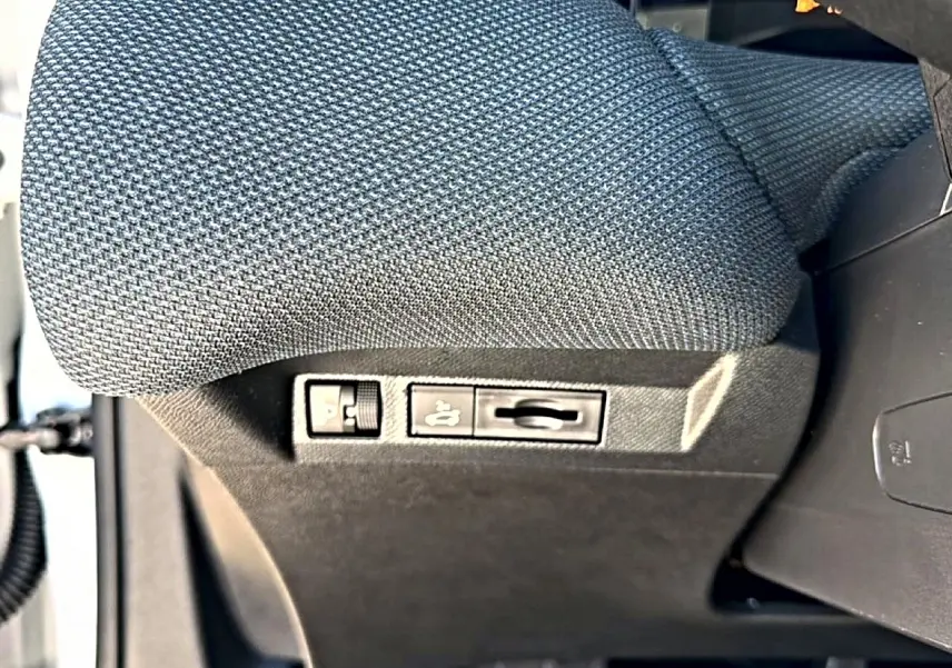 Gros plan sur les commandes de réglage lombaire du siège conducteur en tissu gris du Citroën C5 Aircross hybride 2026.