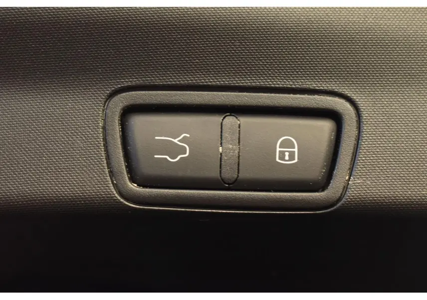 Gros plan sur les boutons d'ouverture du coffre et de verrouillage dans l'habitacle de l'Alfa Romeo Stelvio gris Vesuvio.