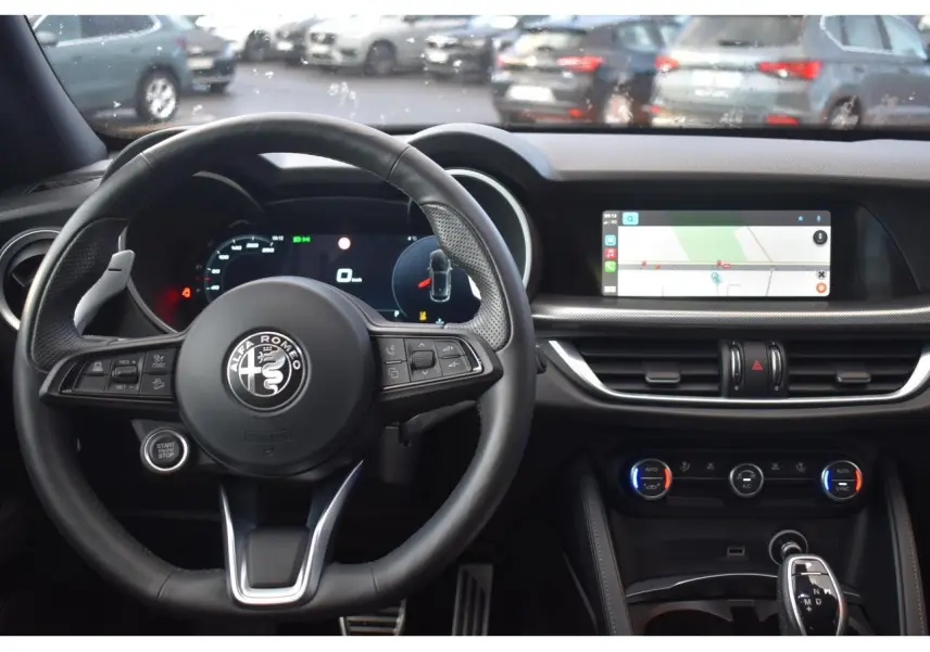 Vue intérieure centrée sur le volant Alfa Romeo Stelvio 2024 avec tableau de bord numérique et écran tactile navigation.