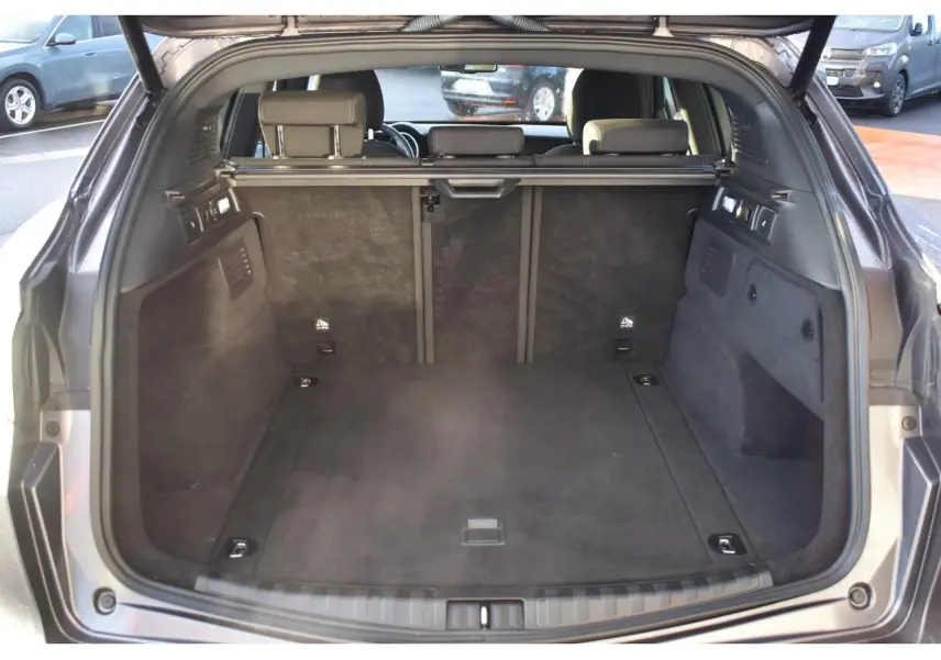 Coffre ouvert vu de l'arrière d'un Alfa Romeo Stelvio gris Vesuvio, montrant l'espace de chargement et les dossiers arrière.
