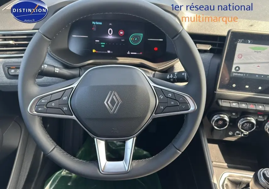 Vue intérieure centrée sur le volant multifonction noir de la Renault Clio V avec tableau de bord numérique et écran tactile.
