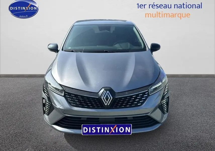 Vue avant d'une Renault Clio V gris schiste avec calandre chromée et phares LED allumés sur fond neutre.