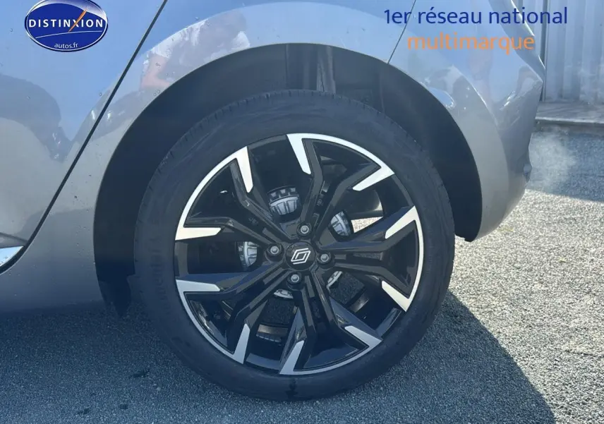 Gros plan sur la jante alu noire et argentée du côté arrière droit d'une Renault Clio V gris schiste.