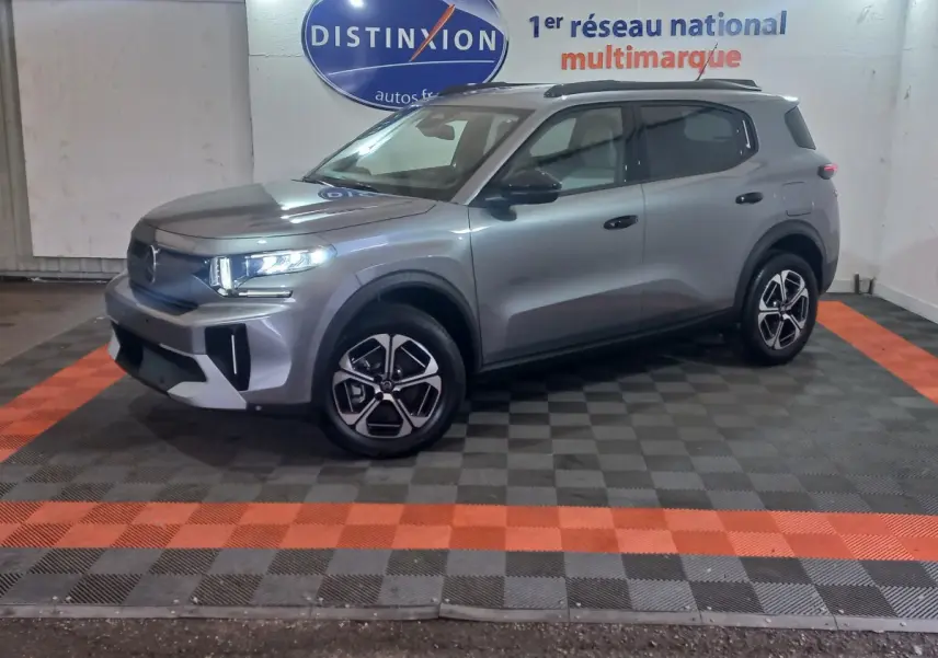 Vue 3/4 avant droit d'un SUV Citroën C3 gris foncé avec jantes noires et détails modernes sur fond intérieur showroom.