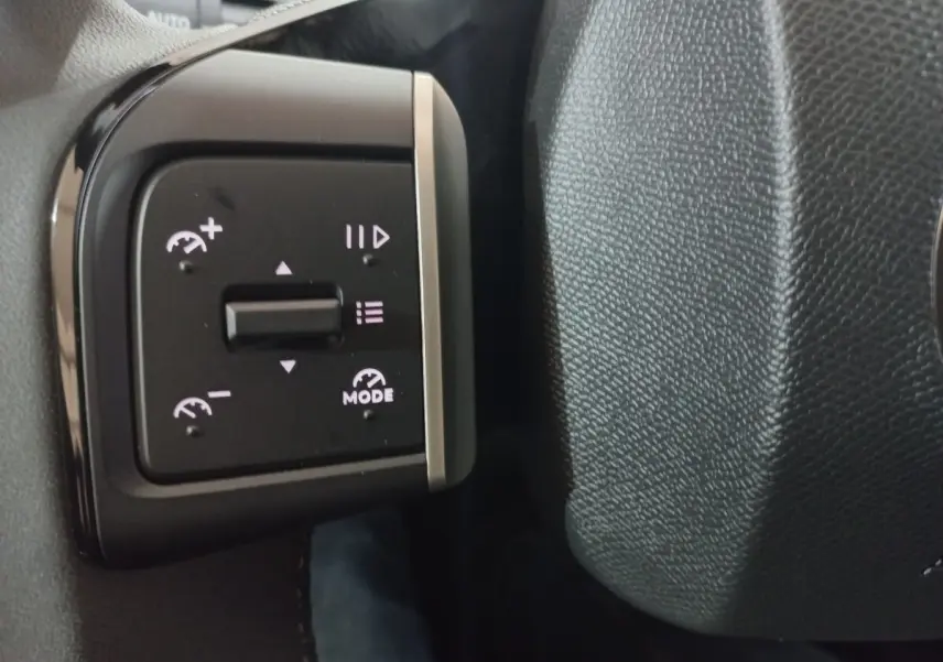 Gros plan sur les commandes de régulateur de vitesse au volant cuir gris foncé d'une Citroën C3 hybride 2025.