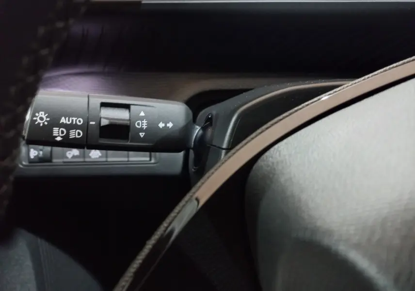 Gros plan sur la commande des phares et clignotants à gauche du volant dans une Citroën C3 gris foncé 2025 hybride.