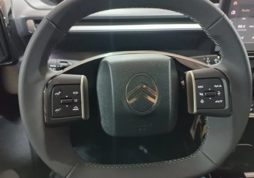 Vue rapprochée du volant cuir noir de la Citroën C3 Hybride 136 e-DSC6 MAX avec commandes multifonctions intégrées.