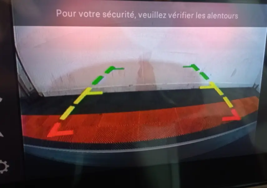 Vue de la caméra de recul de la Citroën C3 hybride gris foncé, avec lignes de guidage colorées et message de sécurité.