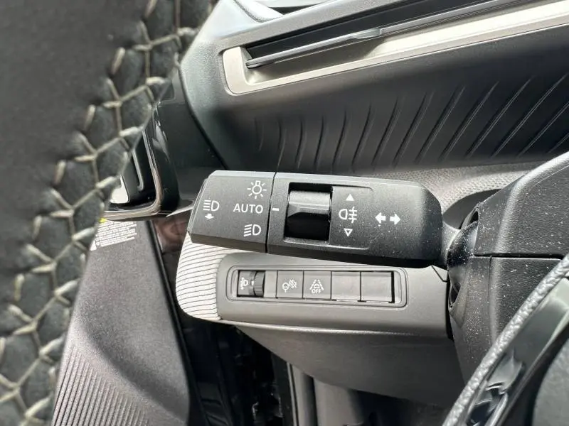 Gros plan sur la commande des feux côté gauche du volant dans l’habitacle noir de la Citroën C3 électrique 2025.