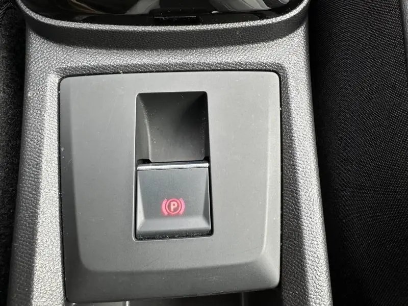 Gros plan sur le bouton de frein de stationnement électrique rouge dans l'habitacle de la Citroën C3 Noir Perla Nera 2025.