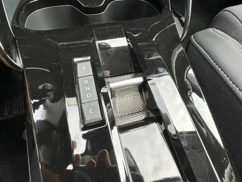 Gros plan sur la console centrale noire brillante de la Citroën C3 électrique 2025 avec la commande de boîte automatique.