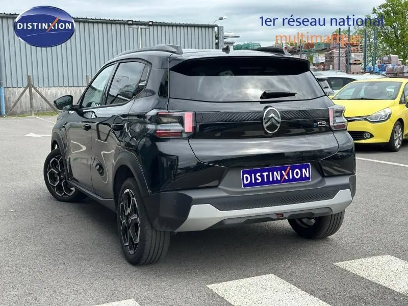 Vue 3/4 arrière droite d'une Citroën C3 électrique 2025 noire Perla Nera avec logo et feux arrière distinctifs.