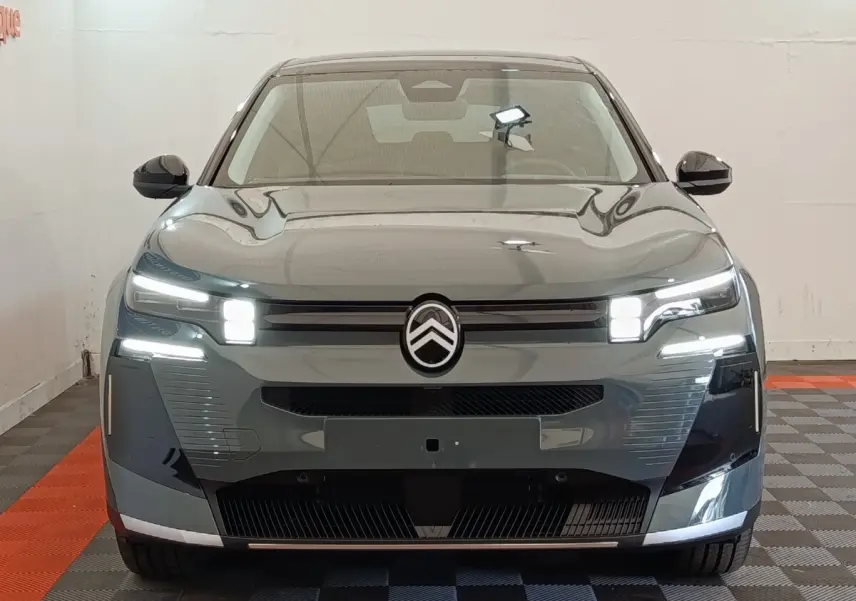 Vue frontale d'une Citroën C5 hybride 2026 vert avec phares LED allumés et logo central distinctif.