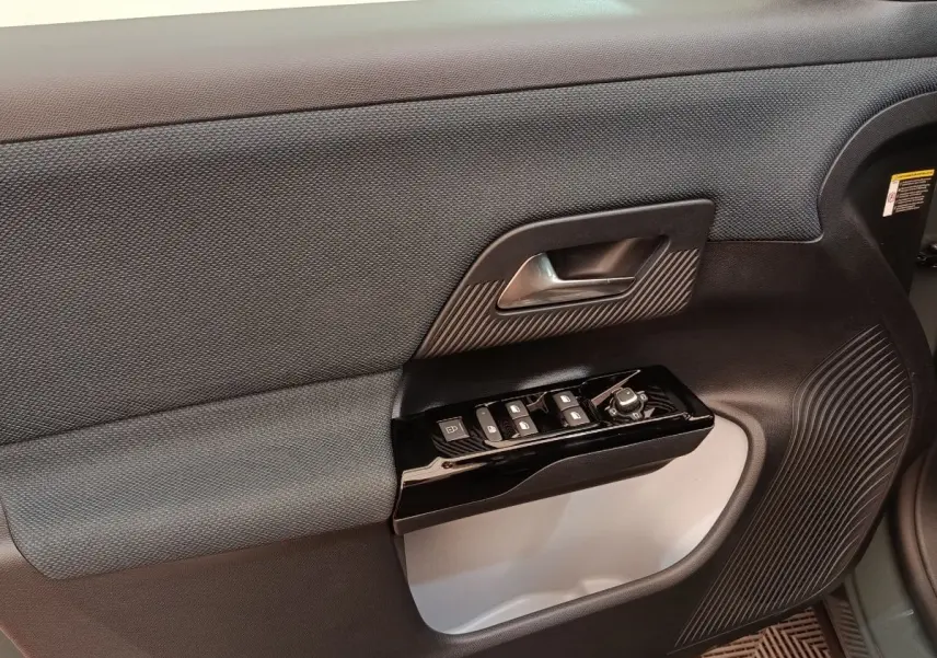Gros plan sur la porte avant gauche intérieure grise et noire du Citroën C5 Hybride 2026 avec commandes électriques.