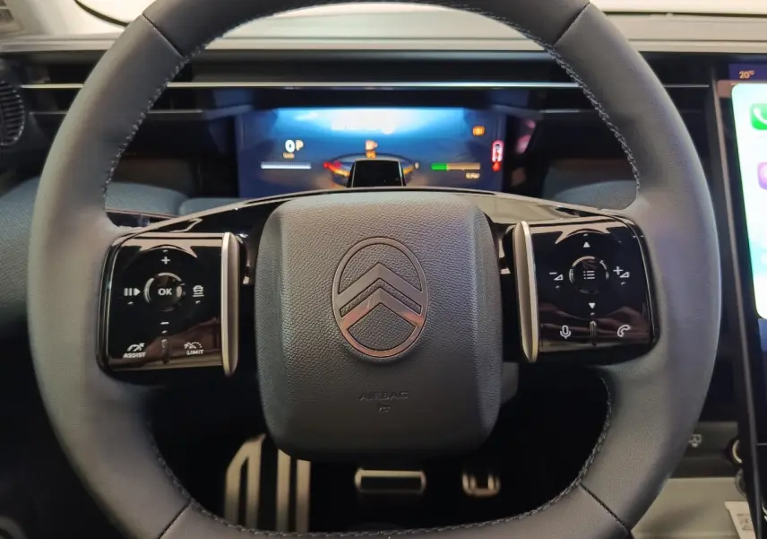 Vue rapprochée du volant cuir noir multifonctions de la Citroën C5 Hybride 2026 avec logo central et commandes tactiles.