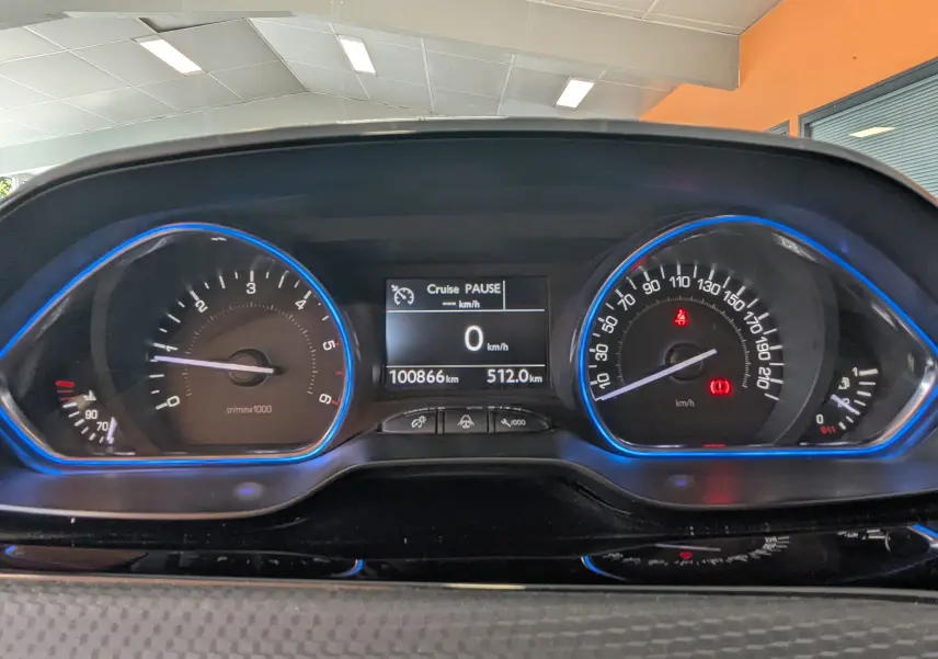 Vue rapprochée du tableau de bord numérique du Peugeot 2008 gris Artense, avec compte-tours et vitesse encadrés de bleu.