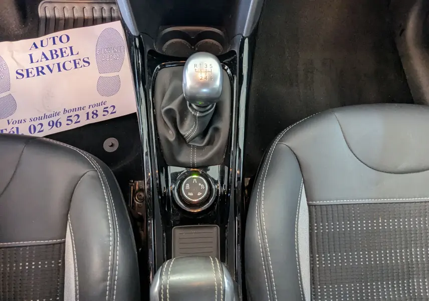 Vue plongeante sur la console centrale du Peugeot 2008 gris, montrant le levier de vitesse manuel et les sièges noirs en tissu.