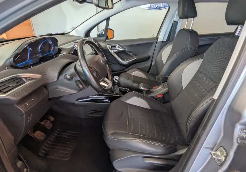 Vue intérieure côté conducteur de la Peugeot 2008 gris artense, avec sièges noirs et tableau de bord moderne.