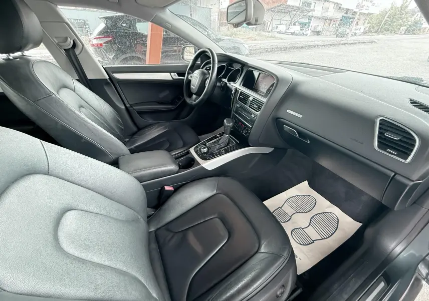 Vue intérieure côté conducteur de l'Audi A5 Sportback 2009 avec sièges cuir noir et tableau de bord gris.