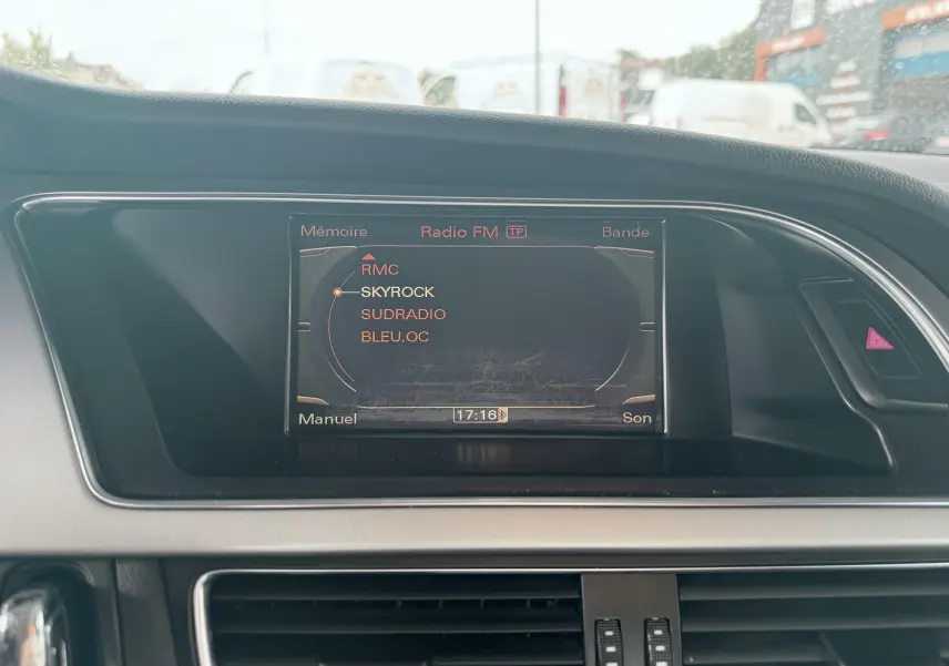 Écran central de l'Audi A5 Sportback 2009 affichant les stations radio FM, entouré de la console noire et grise.