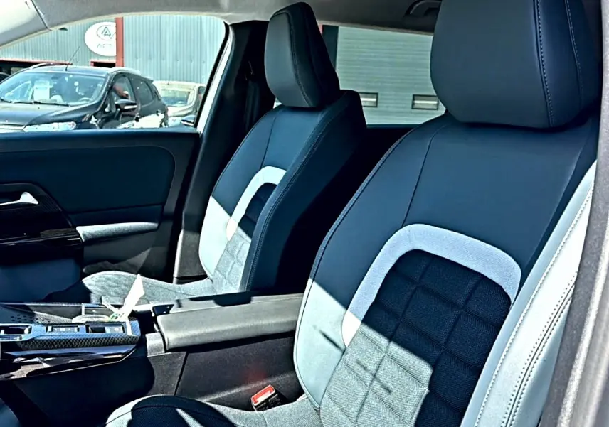 Vue intérieure sur les sièges avant gris et noirs du Citroën C5 Aircross avec accoudoir central et porte-gobelets.