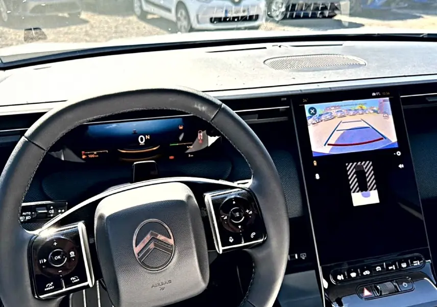 Vue intérieure centrée sur le volant noir multifonction et l'écran tactile affichant la caméra de recul du Citroën C5 Aircross.