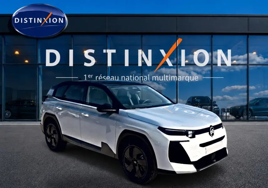 Vue 3/4 avant du Citroën C5 Aircross hybride blanc avec toit noir et jantes alliage noires devant une vitrine Distinxion.