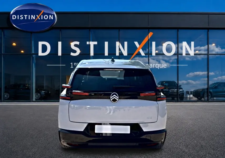 Vue arrière d'un Citroën C5 Aircross blanc et noir avec feux arrière LED, stationné devant une vitrine Distinxion.
