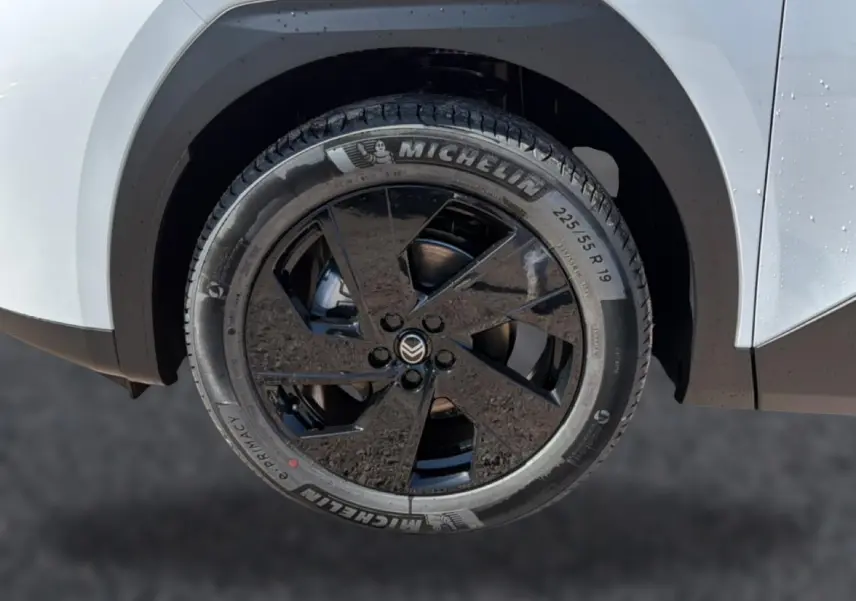 Gros plan sur la roue avant gauche noire et jante alliage 19 pouces du Citroën C5 Aircross blanc et noir.