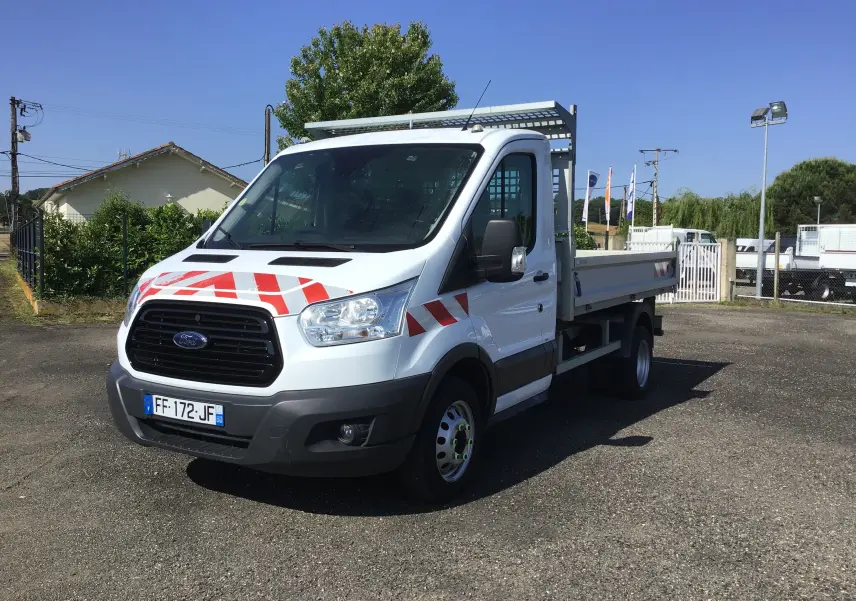 Ford Transit Chassis Cabine blanc vu en 3/4 avant droit avec benne et bandes rouges de signalisation sur la calandre.