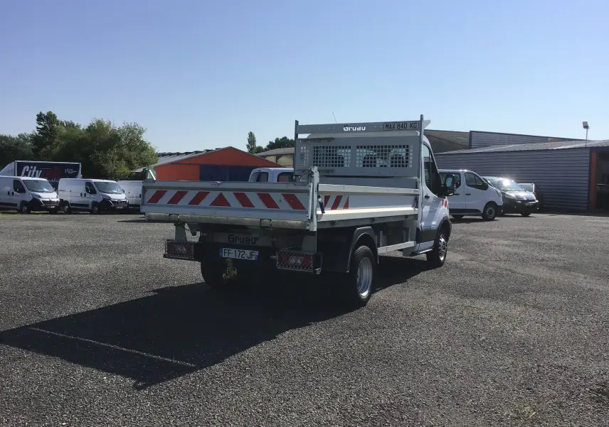 Vue 3/4 arrière droite d'un Ford Transit Chassis Cabine blanc avec benne basculante et marquages rouges réfléchissants.
