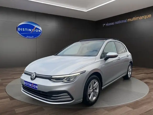 Volkswagen Golf VIII gris argent en 3/4 avant droit, avec toit panoramique ouvrant et vitres surteintées visible en showroom.