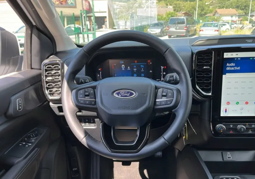 Vue intérieure du tableau de bord du Ford Ranger 2025, volant multifonction et écran tactile central avec interface désactivée.