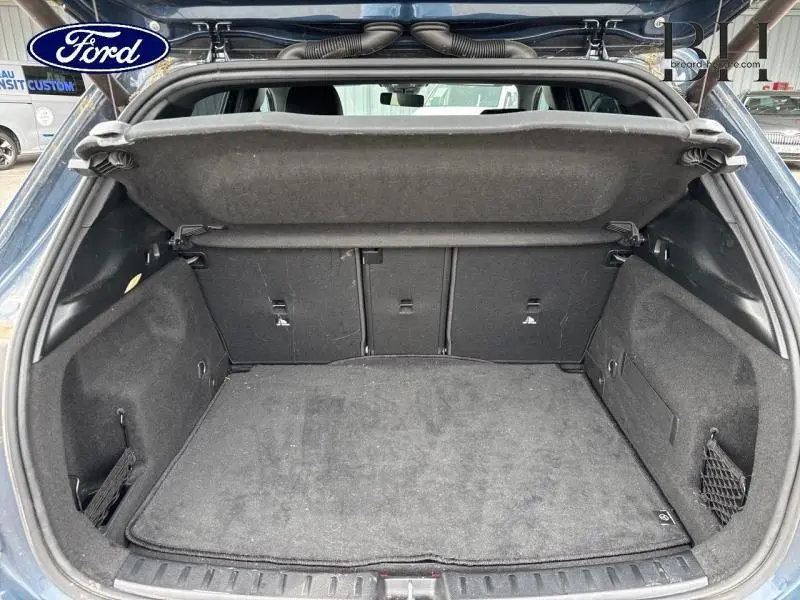 Coffre ouvert d'un Mercedes GLA 250 e bleu denim, montrant l'espace de chargement et la plage arrière relevée.