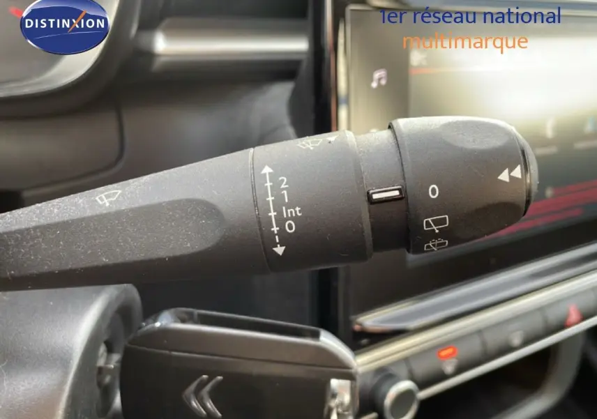 Gros plan sur la commande d'essuie-glace noire dans l'habitacle d'une Citroën C3 blanche au toit rouge.