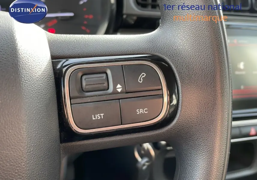 Gros plan sur les commandes au volant noir de la Citroën C3 2018, version 1.2 PureTech, essence, avec boutons de gestion audio et appel.