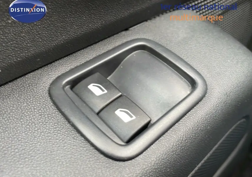 Gros plan sur les boutons de commande des vitres électriques côté conducteur d'une Citroën C3 blanche avec toit rouge.